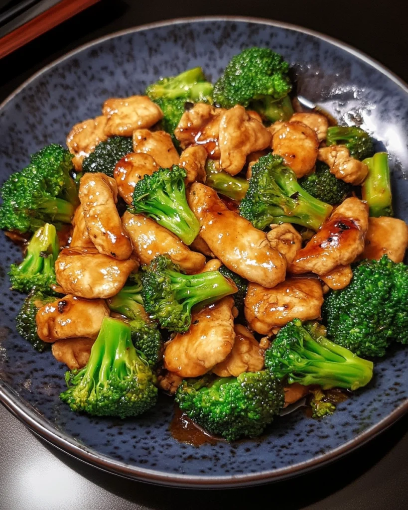 Savory stir-fried tender chicken with crisp broccoli in garlic soy glaze served in a white ceramic bowl